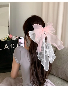Detail of pink mesh bow and white lace embroidery ribbon hair clip on female model