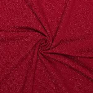 Détail du tissu en maille rouge avec paillettes brillantes et texture drapée élégante