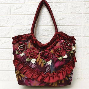 Detailed close-up of handmade 3D silk roses and ruffles on a burgundy shoulder bag