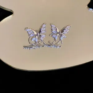 Elegant silver butterfly ear cuffs with sparkling zircons on a luxury mirror display