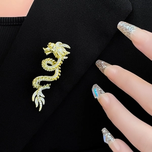 Detailed close-up of a gold-plated dragon brooch with rhinestones on a black suit