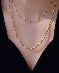 Detail of layered gold beaded necklaces on a model wearing a black V-neck top