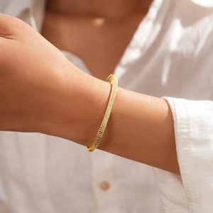 Detailed close-up of 18k gold-plated textured bangle with elegant vertical stripe texture