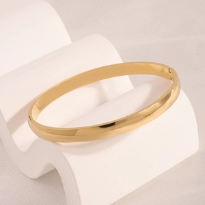 Detailed macro view of gold-plated curved bangle with polished finish and hinge closure