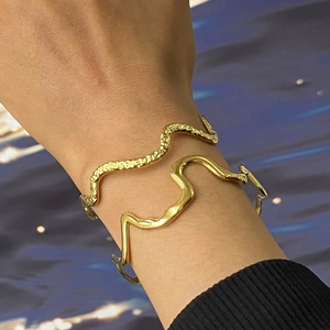 Detail of gold wavy stainless steel bangles with smooth and hammered texture on wrist