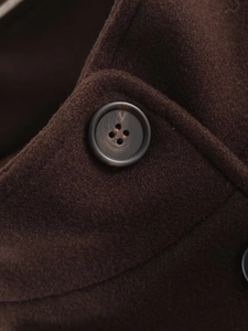 Detailed macro view of dark brown wool coat featuring high-quality faux horn buttons