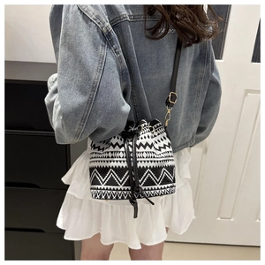 Detailed view of canvas bucket bag with black and white geometric patterns and leather strap