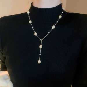 Elegant gold-plated Baroque pearl Y-shaped necklace worn on a black knit sweater