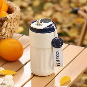 Close-up of smart coffee cup with temperature display, white body and blue lid details