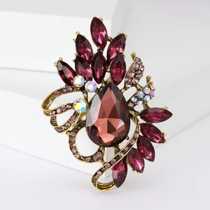 Macro shot of vintage brooch featuring a large pear-shaped purple gemstone and pink rhinestones