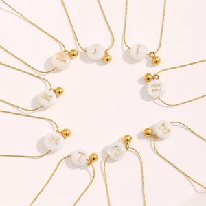 Detail of 18K gold plated stainless steel necklaces with white alphabet shell charms