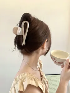 Detail of a cream resin shark hair claw clip styled on a model in a French aesthetic