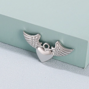 Polished silver heart pendant with angel wings on a minimalist green cube background