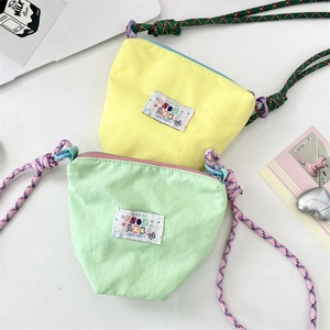 Close-up of textured nylon phone bags in yellow and green with colorful braided rope straps