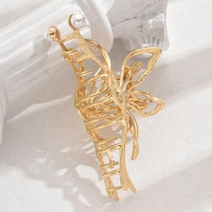 Macro detail of golden butterfly metal hair claw with elegant faux pearl accents