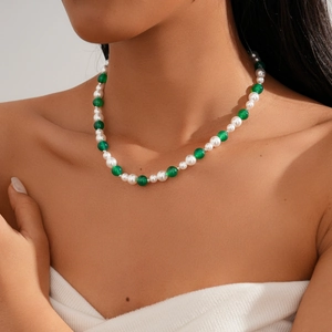 Close-up of retro beaded necklace with white pearls and green agate stones on neck