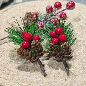 Artificial Christmas picks with red berries pine needles and cones on wood background