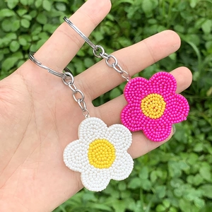 Detailed view of handmade beaded daisy flower keychains in white and pink colors