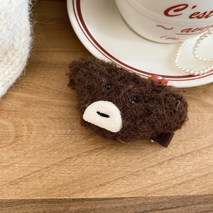Close-up of a brown plush bear hair clip with soft lamb wool texture and metal duckbill clip