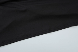 Detail of flat seam stitching on the hem of a black knitted asymmetrical dress