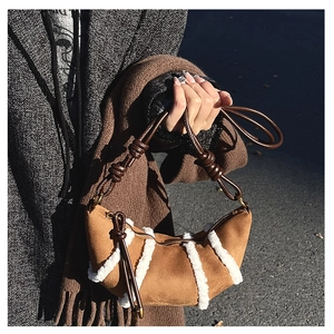 Detail der braunen Wildleder-Halbmondtasche mit Sherpa-Besatz und geflochtenem Riemen