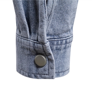 Gros plan du poignet d'une veste en jean délavé bleu clair avec bouton argenté mat