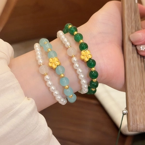 Detalle de pulseras de piedra natural y perlas con refinados motivos de flores doradas