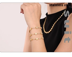 Detailed view of layered 18K gold-plated stainless steel bar bracelets and matching necklace