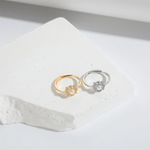 Detail of gold and silver flower rings with pearls and diamonds on a stone base