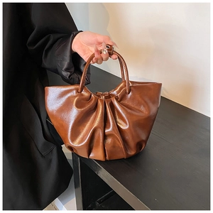 Detailed close-up of brown ruched leather handbag showing glossy texture and cloud design