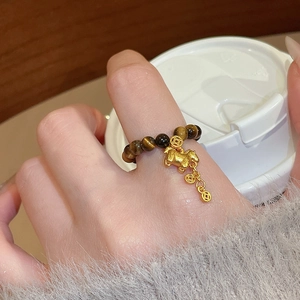 Detailed shot of tiger eye beaded ring with golden mascot and coin charms