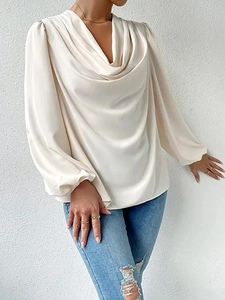 Close-up of elegant cowl neck and silky satin texture on cream long sleeve blouse