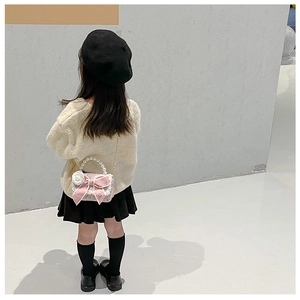Pink girl purse with pearl handle and oversized bow shown as crossbody bag for kids