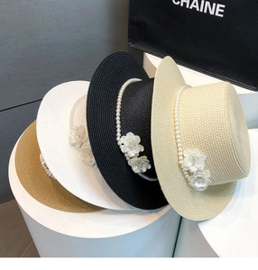 Detail of straw boater hats with elegant fabric flowers and pearl strand decorations