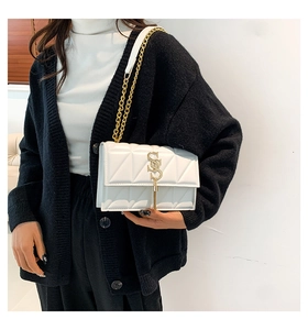 Close-up of white quilted PU leather handbag with gold chain strap and elegant tassel