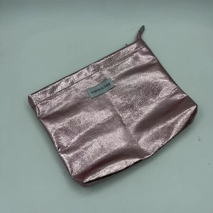 Detail of pink metallic PU leather makeup bag with textured foil finish and zipper