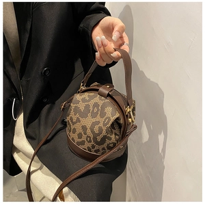 Detailed shot of leopard print cylinder bag featuring dark brown leather and gold hardware