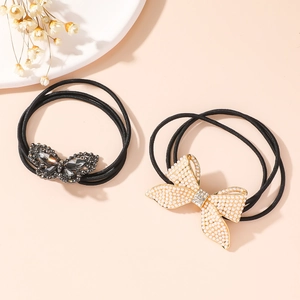 Detailed view of elastic hair ties with black rhinestone butterfly and faux pearl bow decor