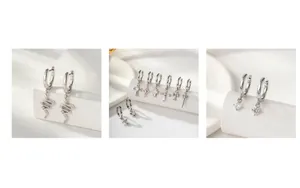 Detailed view of silver snake pendants and cross earrings with minimalist star studs