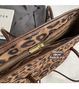 Detail of the smooth golden metal zipper and leopard print fabric on a tote bag