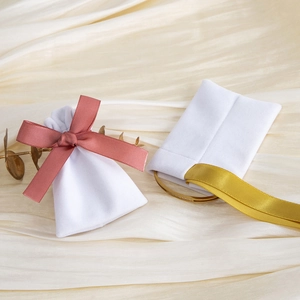 Detailed view of white velvet jewelry pouches with elegant pink and gold silk ribbons