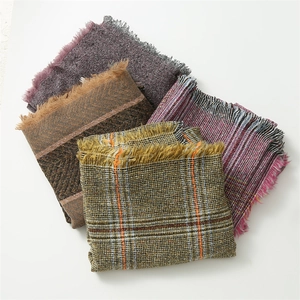 Detail view of multi-color knitted scarves with bouclé yarn textures and fringe edges