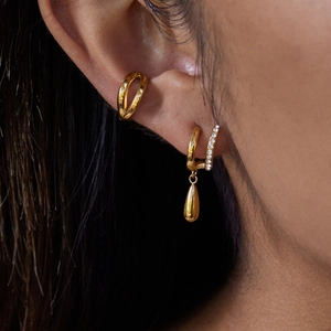 Gros plan de boucles d'oreilles en acier titane doré avec pendentif goutte d'eau lisse