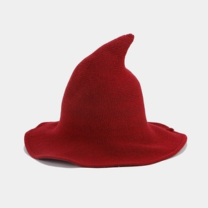 Macro detail of red knitted pointed wizard hat showing the fine wool texture and wavy brim