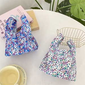 Close-up of floral corduroy wrist bags in purple and blue tones on a white desk