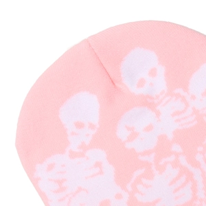 Detailed macro view of the pink knit beanie featuring white skull and bone patterns