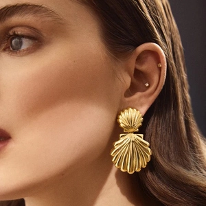 Detailed close-up of double shell drop earrings in 18K gold finish worn by a model