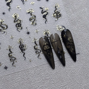 Gothic nail art stickers with gold mystical snake and sun patterns on black background