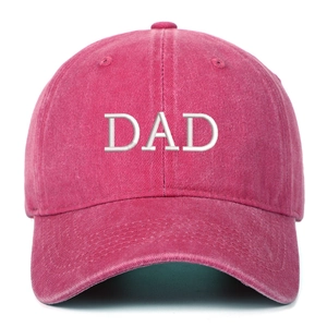 Close-up of vintage washed red cotton baseball cap with white DAD embroidery and texture
