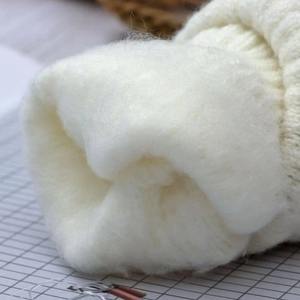 Detailed macro view of the thick white fleece lining in beige knitted winter gloves